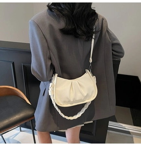 Detail of creamy white dumpling bag with woven handle and litchi texture finish