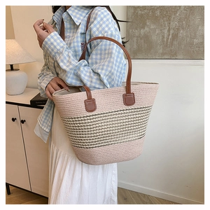 Dettaglio della borsa tote in paglia intrecciata rosa e beige con manici in pelle marrone