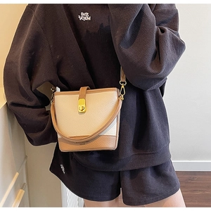 Détail du sac seau bicolore en cuir grainé avec fermoir rotatif en métal doré