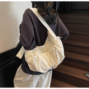 Detail of cream canvas dumpling bag showing drawstring texture and adjustable buckle