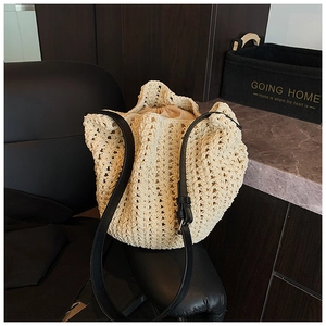 Close-up of cream woven bucket bag with intricate cutout texture and adjustable black strap