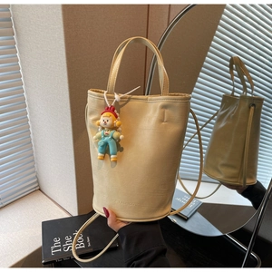 Detail of cream faux leather bucket bag with embossed FASHION logo and cute girl charm