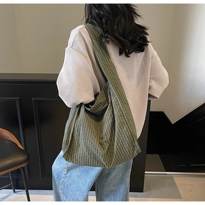 Rear view of model wearing a large green checkered canvas tote bag in a modern room
