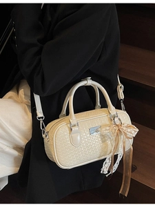 Borsa Boston beige intrecciata da donna con ciondolo in pizzo vista su una scala