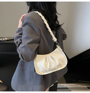 Close-up of elegant ruched white underarm bag with a stylish braided shoulder strap