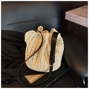 Detail of cream crochet bucket bag with black adjustable leather strap and silver buckle