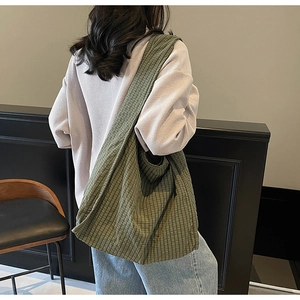 Close-up of green checkered canvas tote bag showing the spacious slouchy design on a model