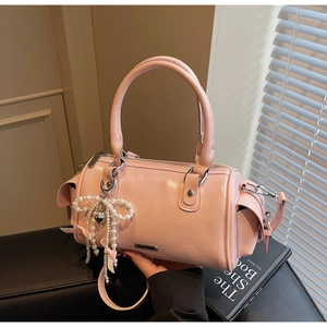 Dettaglio borsa Boston rosa con fiocco di perle e ciondolo a cuore su base in pelle