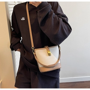 Détail du sac seau bicolore en cuir à texture litchi avec boucle en métal doré poli
