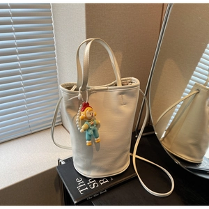 Close-up of white PU bucket bag featuring a cute girl charm and embossed fashion text