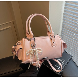Dettaglio borsa Boston rosa in pelle opaca con elegante ciondolo a fiocco di perle