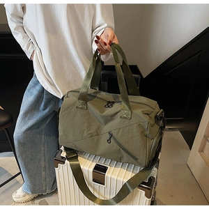 Detail view of large dark green travel duffel bag on a suitcase showing fabric texture