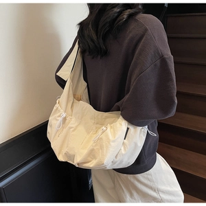 Detail of cream dumpling bag showing large capacity, side pockets, and adjustable drawstrings