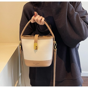 Détail d'un sac seau blanc et kaki avec texture litchi et fermoir doré rotatif élégant