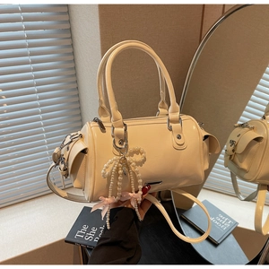 Dettaglio borsa Boston beige con ciondolo a fiocco di perle e tracolla regolabile