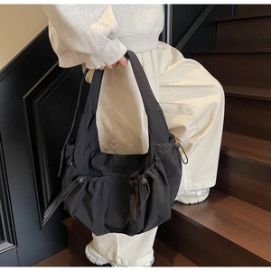 Detail of adjustable side drawstring on black large capacity nylon shoulder tote bag