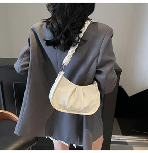 Detail view of cream dumpling bag with pleated leather texture and braided strap