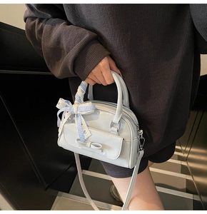 Detail of light blue patent leather handbag with checkered bow and silver metal hardware