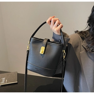 Détail du sac seau noir en cuir avec boucle dorée et lettrage de marque élégant