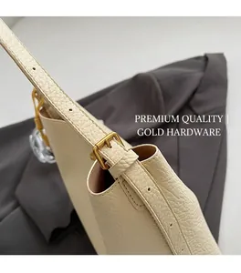 Close-up of lychee textured cream leather shoulder bag with matte gold metal buckle