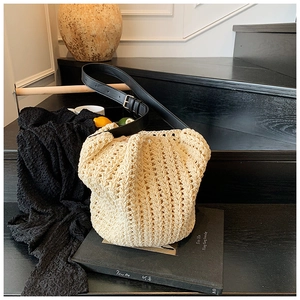Detail of cream crochet bucket bag featuring hollow woven texture and black leather strap