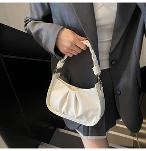 Detail of white ruched crescent bag featuring a woven handle and silver hardware accent