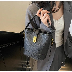 Détail du sac seau noir en cuir grainé avec fermoir rotatif en métal doré chic