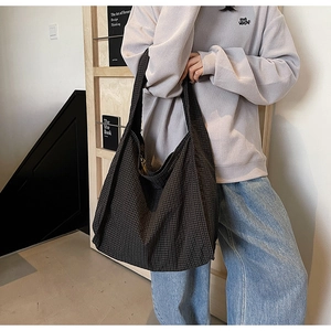 Detail of soft dark grid canvas tote bag worn by model in a casual lifestyle setting