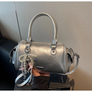 Detail of silver Boston bag with pearls and pink bow charm on polished material