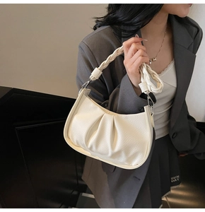 Detail of off-white pleated underarm bag with lychee texture and woven handle