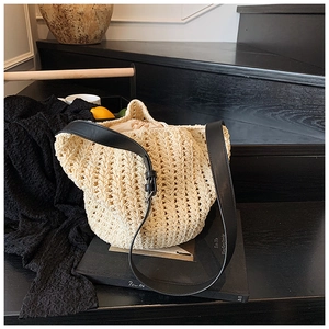 Detail of woven straw bucket bag showing beige drawstring lining and black leather strap