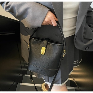 Détail d'un sac seau noir grainé avec fermoir doré et poignée élégante en gros plan