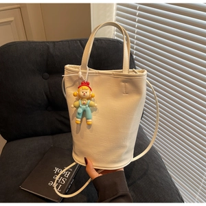 Detail of white crocodile embossed bucket bag featuring a fashion pendant on a black seat