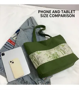 Détail du sac cabas en toile verte avec motif bambou présenté à côté d'un iPad pour la taille