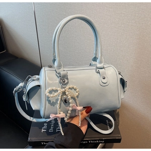 Dettaglio della borsa Boston azzurra con finitura lucida e ciondolo a fiocco di perle