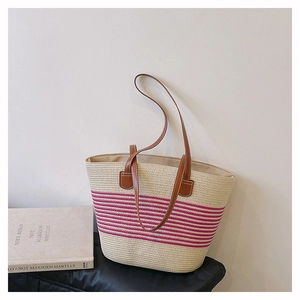 Dettaglio della borsa tote in paglia con strisce rosa e manici in pelle chic