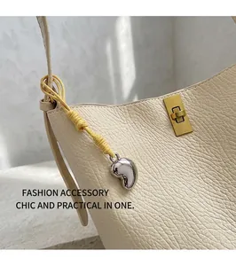 Detail of beige hobo bag with gold twist lock and silver heart charm on textured leather