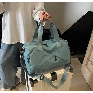 Close-up of light blue waterproof travel bag with adjustable strap on white luggage