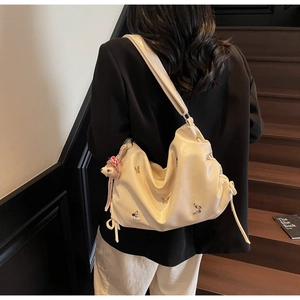 Detail of creamy white pleated crossbody bag with silver butterflies and rabbit charm