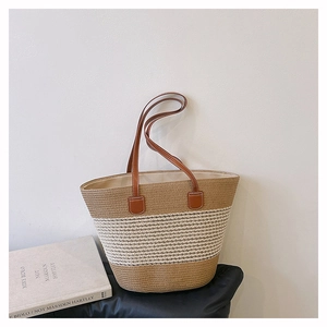 Dettaglio borsa tote in paglia intrecciata con strisce beige e manici in pelle marrone