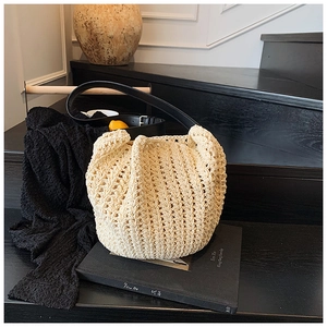 Detail of beige hand-woven crochet bucket bag with black leather strap on stairs