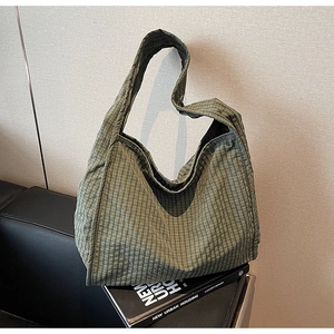 Close-up of green checkered canvas tote bag placed on a book in a minimalist urban setting
