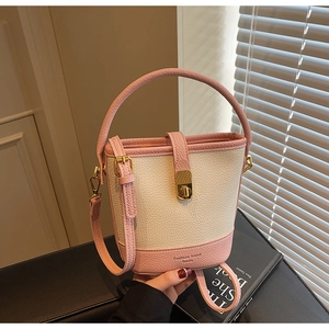 Gros plan du sac seau rose et crème avec texture grainée et boucle dorée