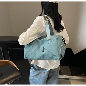 Detail view of light blue travel bag with diagonal zipper pocket and adjustable strap