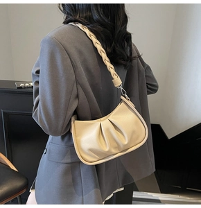 Detail of beige pleated shoulder bag with textured leather and woven handle detail