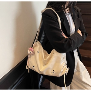 Detail of cream pleated crossbody bag featuring butterfly prints and a plush fox charm