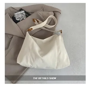 Detail of off-white tote bag with textured fabric, brown leather trim and gold metal hardware