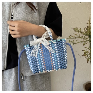 Detail of hand-woven basket bag with blue geometric pattern and white lace bow