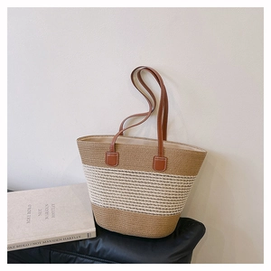 Dettaglio della borsa tote in paglia intrecciata a mano con colori a contrasto e manici