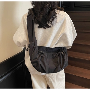 Close-up of black drawstring dumpling bag with pleated nylon fabric for casual street style